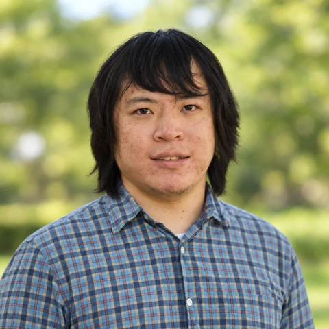 Sikao Guo, wearing a blue checked shirt, outdoors